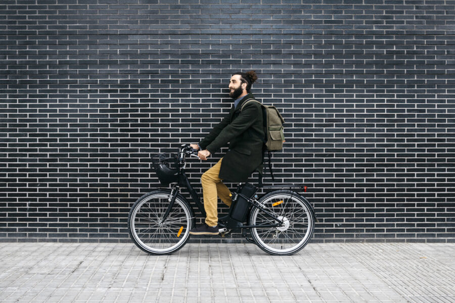 Man riding e-bike along a brick wall